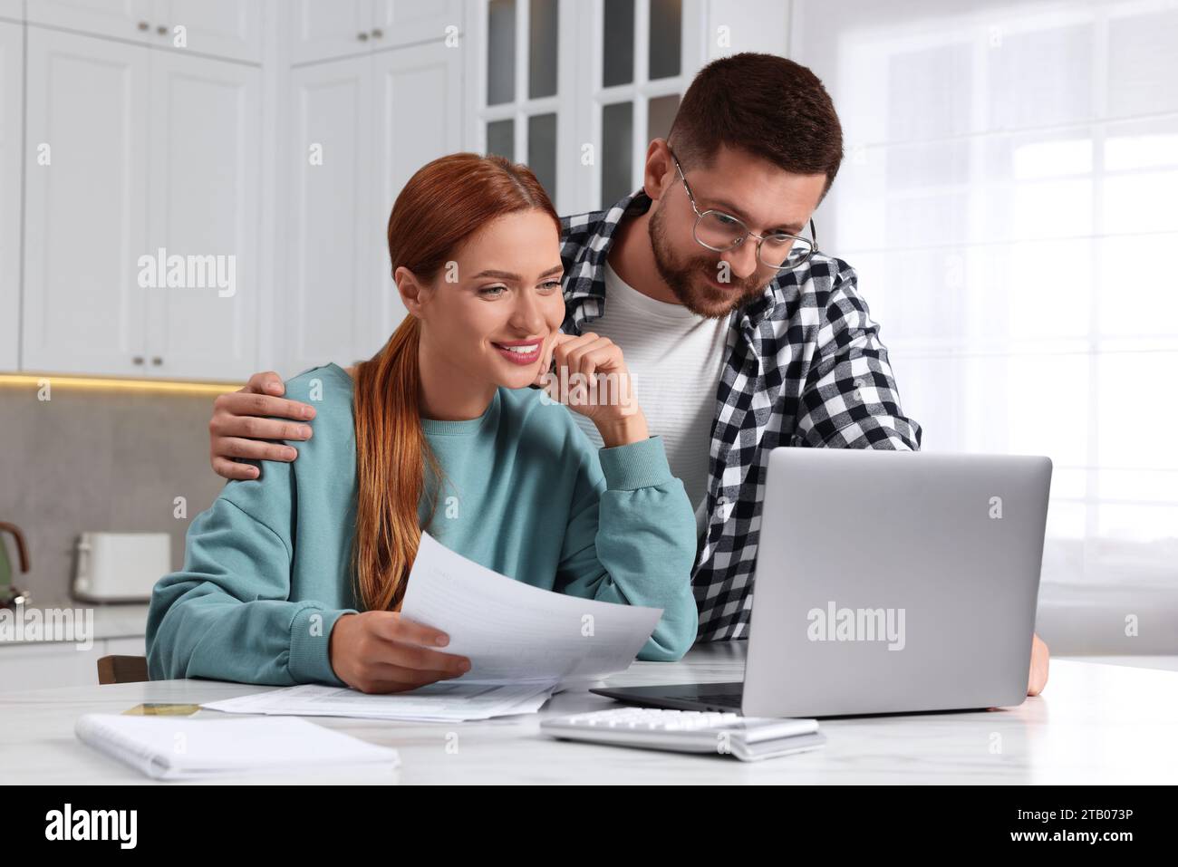 Couple utilisant un ordinateur portable pour payer des impôts à la maison Banque D'Images