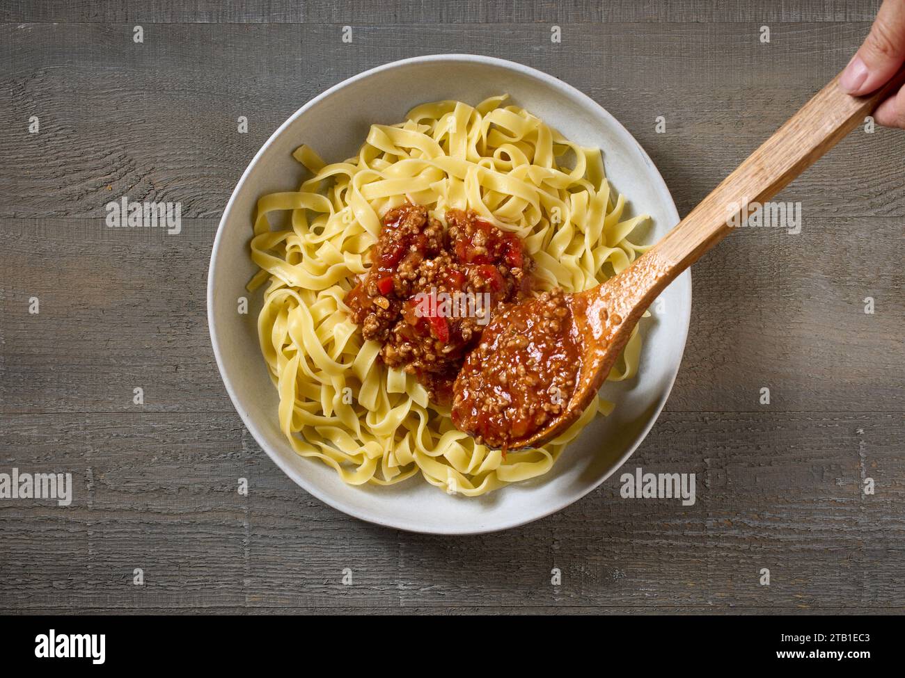 la sauce bologne est ajoutée à un bol de pâtes, vue de dessus Banque D'Images