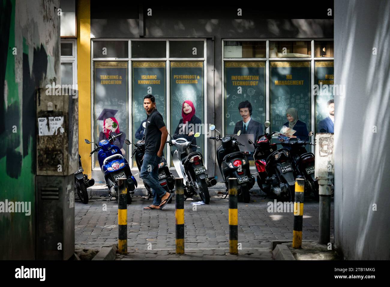 Maldives. 04 décembre 2023. Un homme passe devant une école d'enseignement supérieur à Malé. Vie quotidienne à Malé, aux Maldives, capitale de la nation insulaire de l’océan Indien, dont l’économie dépend fortement du tourisme. La population du pays comprend de nombreux ressortissants étrangers travaillant dans des pays du monde entier, y compris les Philippines, le Myanmar, le Sri Lanka et l'Inde, et sa population est majoritairement musulmane. Crédit : Matt Hunt/Neato/Alamy Live News Banque D'Images