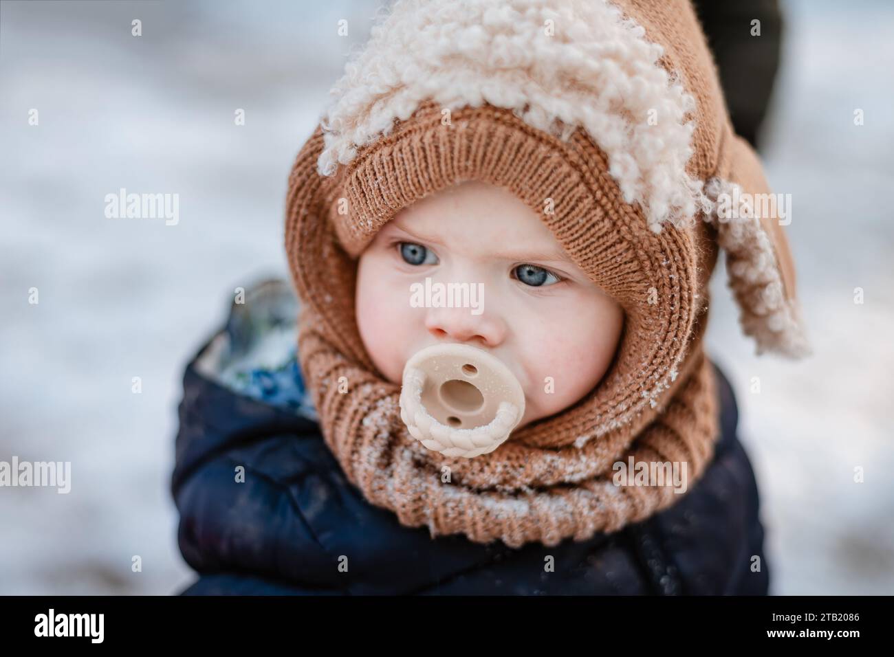 Gros plan sur le visage d'un enfant habillé pour l'hiver avec une sucette Banque D'Images