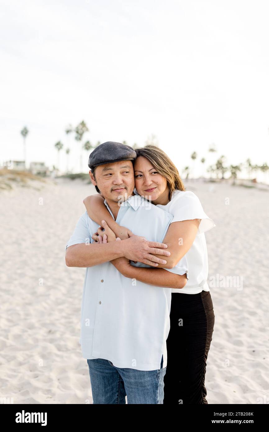 Mari et femme asiatiques embrassent sur la plage au coucher du soleil à San Diego Banque D'Images