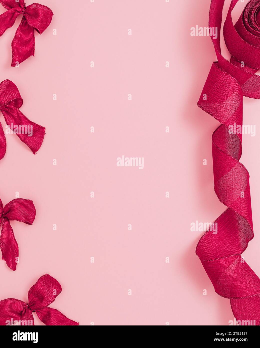 Ruban rouge et arcs de noël sur un fond rose avec espace de copie Banque D'Images