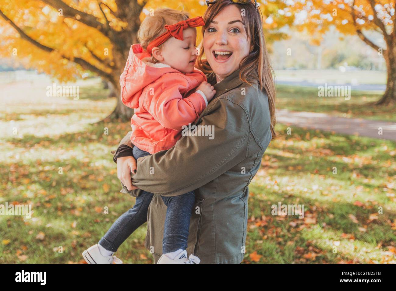 Maman souriante tenant une petite fille le jour de l'automne Banque D'Images