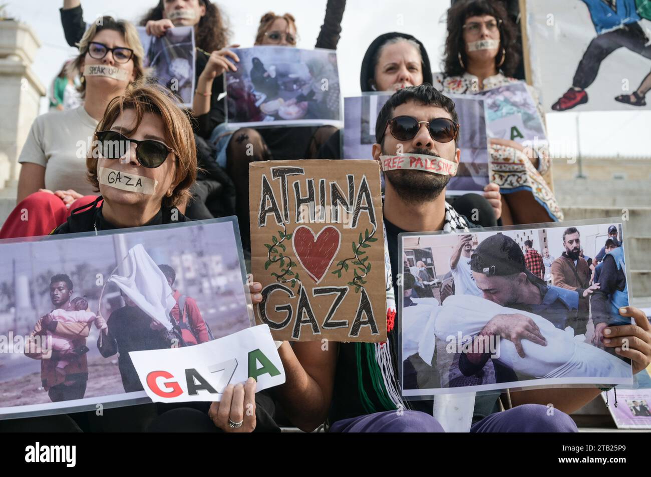 Athènes, Grèce. 3 décembre 2023. Les manifestants brandissent une banderole sur laquelle on peut lire Athina - Athènes aime Gaza. Des manifestants pro palestiniens qui se sont fermés la bouche et tiennent des photos des atrocités de guerre à Gaza manifestent devant le Parlement grec dimanche. Crédit : Dimitris Aspiotis/Alamy Live News Banque D'Images