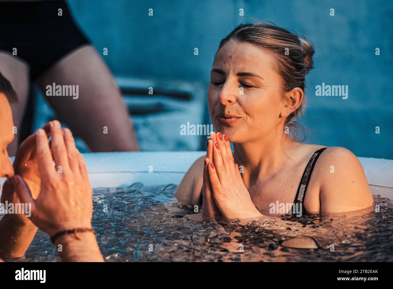 Femme bain de glace dans l'eau froide parmi les glaçons dans une piscine gonflable. Méthode Wim Hof, thérapie par le froid, techniques de respiration, yoga et méditation Banque D'Images