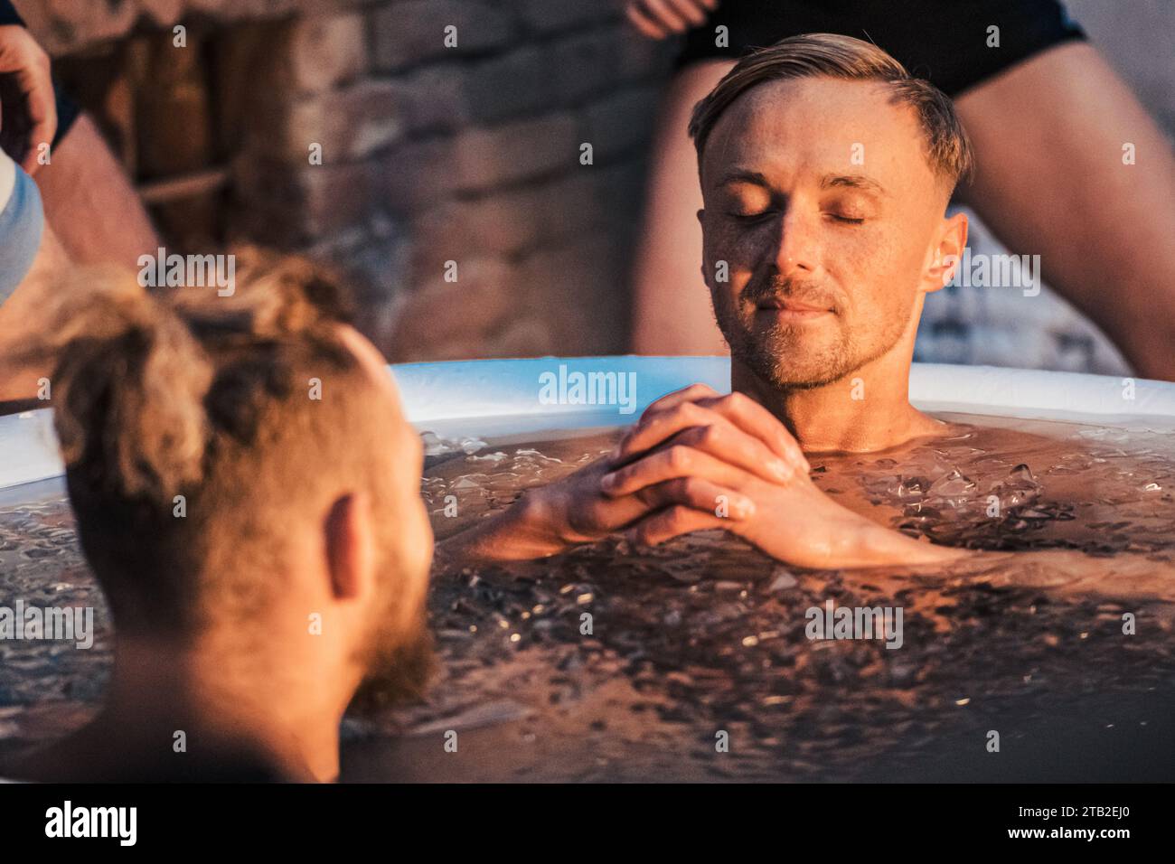 Beau garçon ou homme bain de glace dans l'eau froide parmi les glaçons. Méthode Wim Hof, thérapie par le froid, techniques de respiration, yoga, méditation Banque D'Images