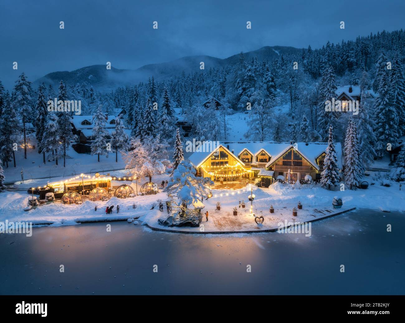 Vue aérienne de maisons illuminées dans un village enneigé la nuit Banque D'Images