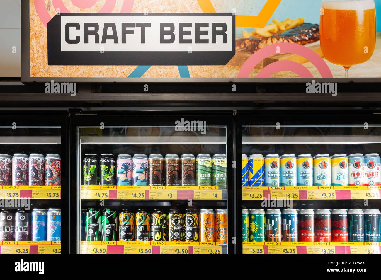 Une collection diversifiée de bières artisanales froides en canettes, avec un panneau publicitaire de bière artisanale ci-dessus, dans des réfrigérateurs en vente au supermarché Morrisons, en Angleterre Banque D'Images