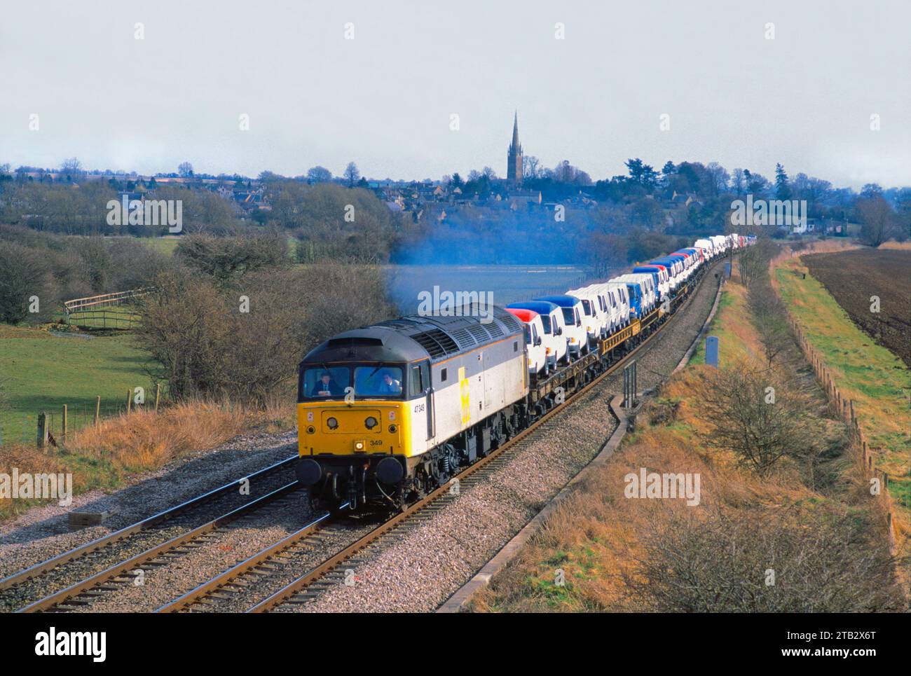Une locomotive diesel de classe 47 numéro 47349 se dirige vers le nord avec un long train de fourgonnettes Ford à Kings Sutton le 1 avril 1995. Banque D'Images