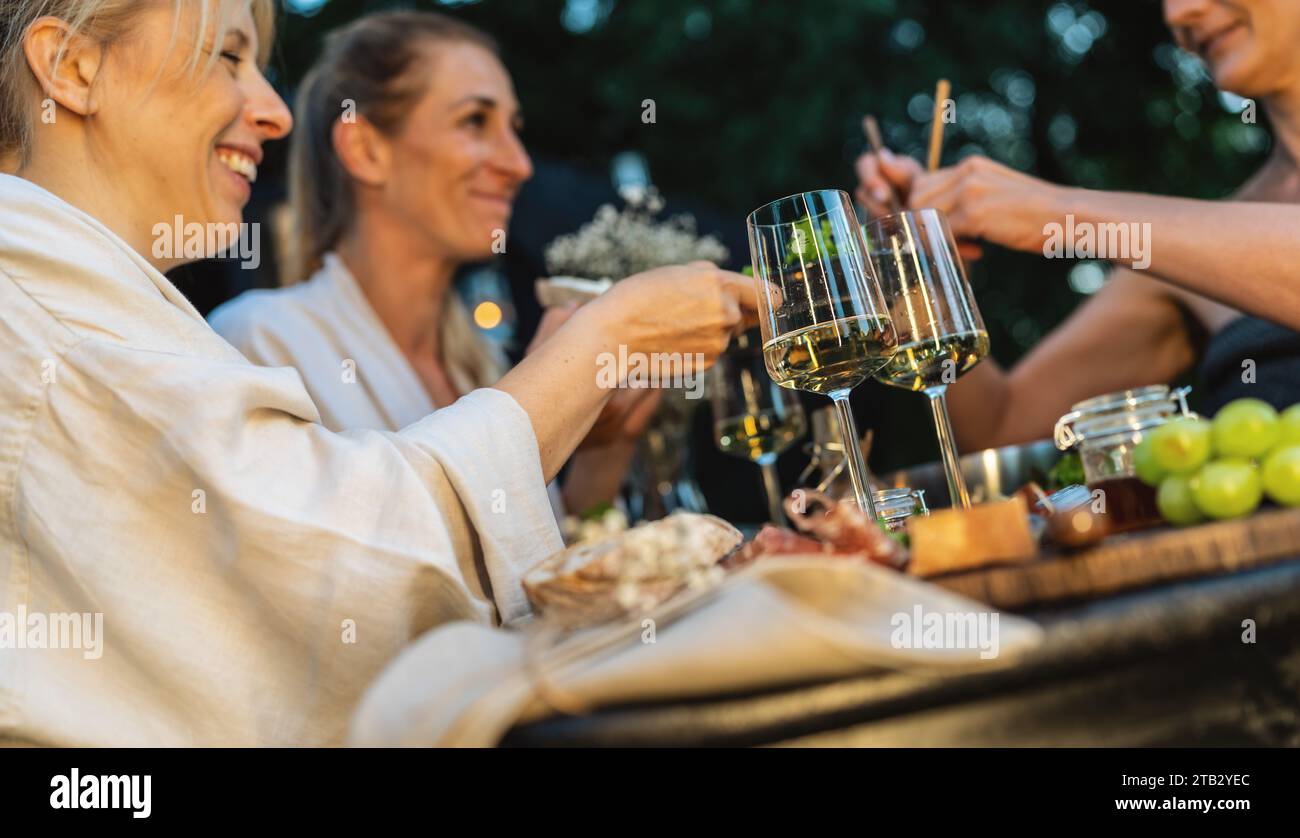 Les amis apprécient le vin et la nourriture à l'extérieur près d'un sauna mobile finlandais au crépuscule Banque D'Images
