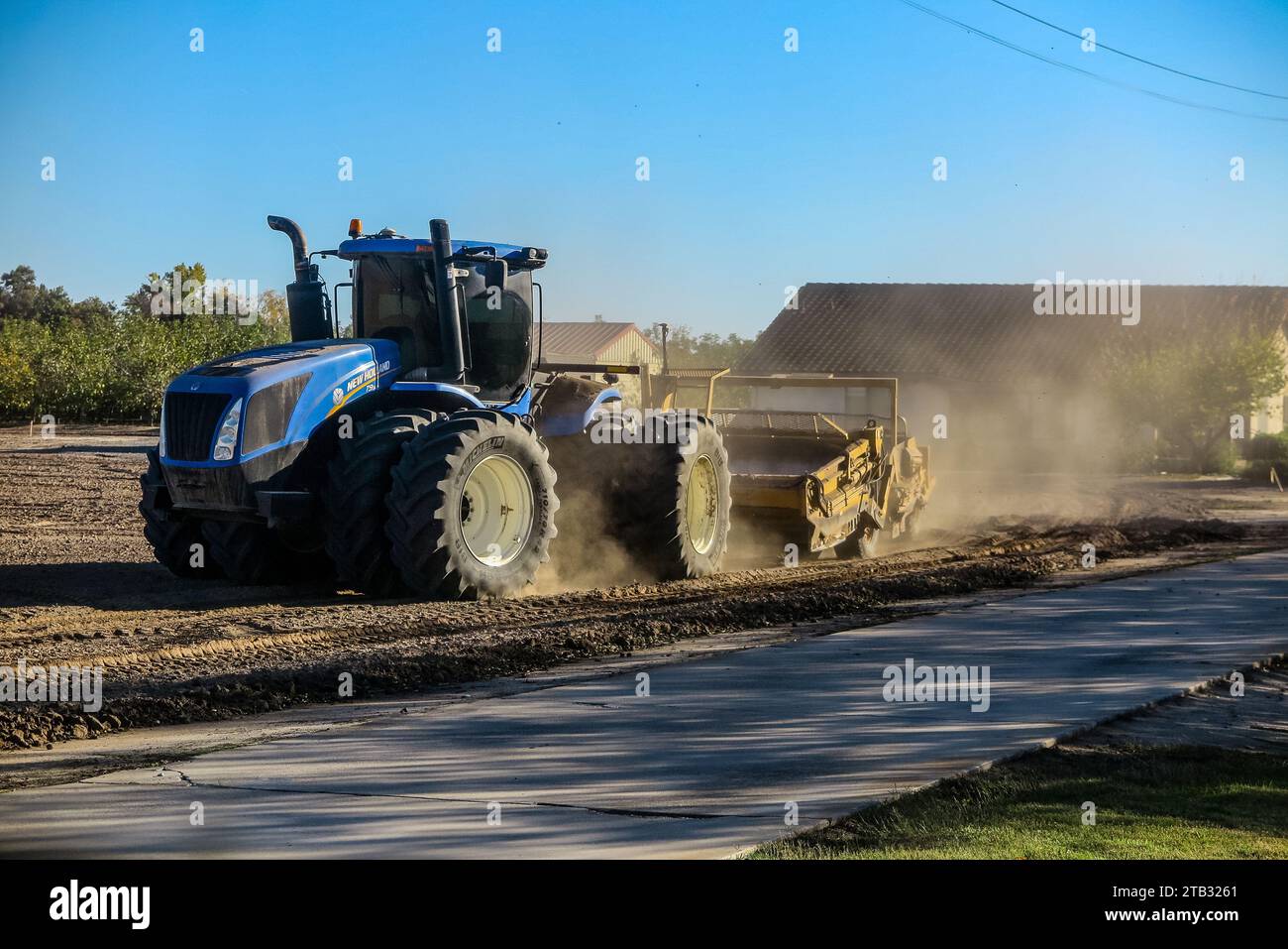 Un tracteur tire des grattoirs guidés au laser pour niveler un ancien verger de noyer afin de le préparer à planter de nouveaux arbres dans la vallée centrale de Californie, aux États-Unis Banque D'Images