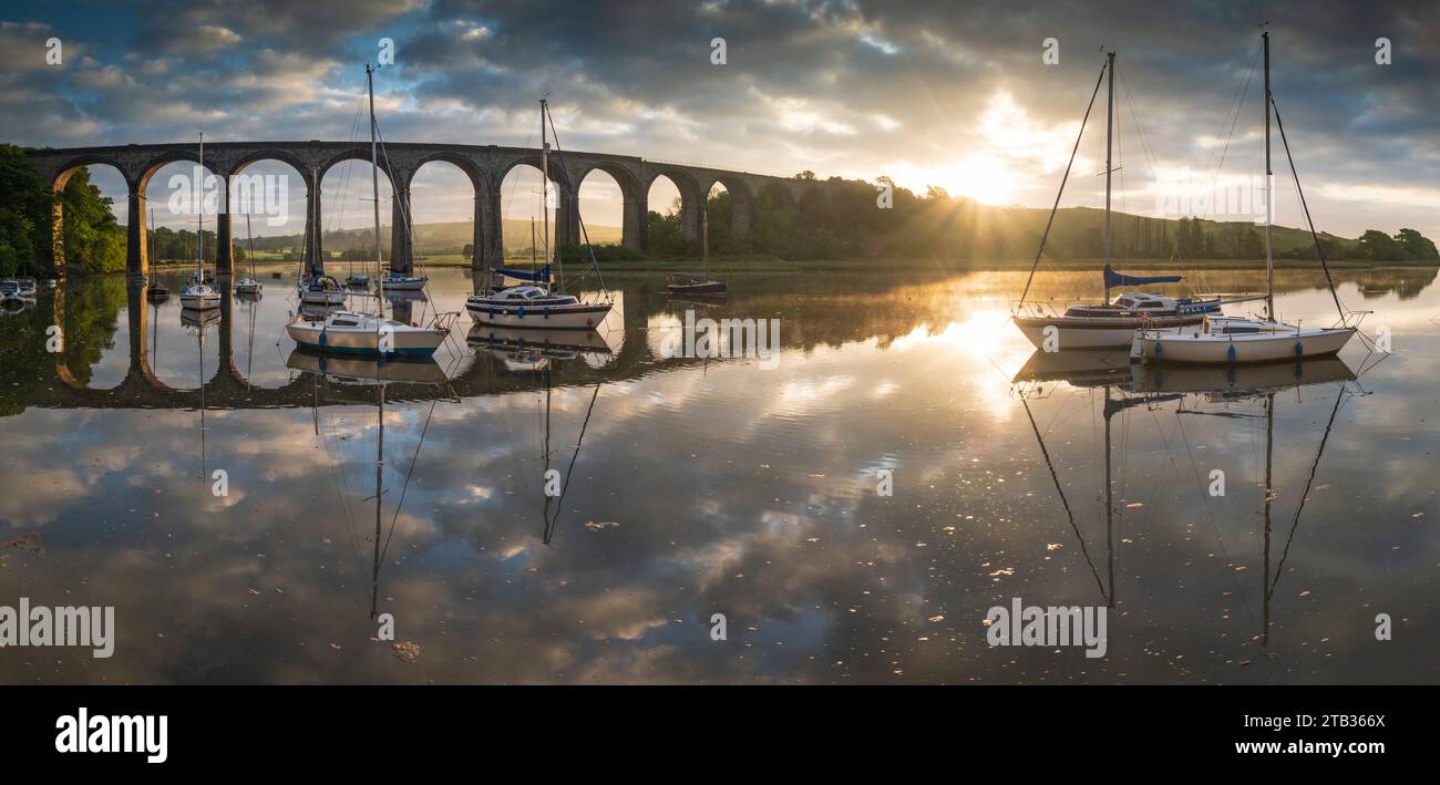 Bateaux amarrés sur la rivière Tiddy à l'aube sous le viaduc victorien à St Germans, Cornouailles, Angleterre. Printemps (mai) 2022. Banque D'Images