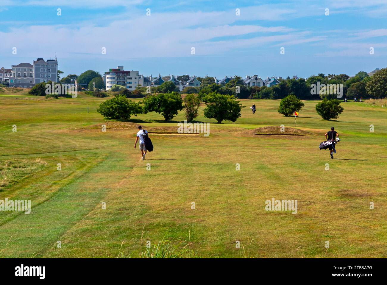 Golfeurs se promenant à travers Hythe Golf Club près de Folkestone dans le Kent Angleterre Royaume-Uni en été avec un ciel bleu au-dessus. Banque D'Images