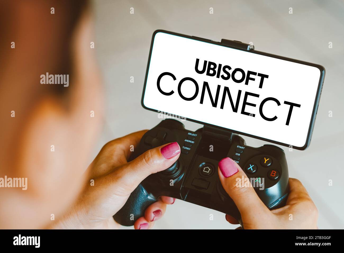 Sur cette photo, le logo Ubisoft Connect est affiché sur l'écran d'un smartphone lorsqu'une personne joue sur une manette de jeu. Banque D'Images