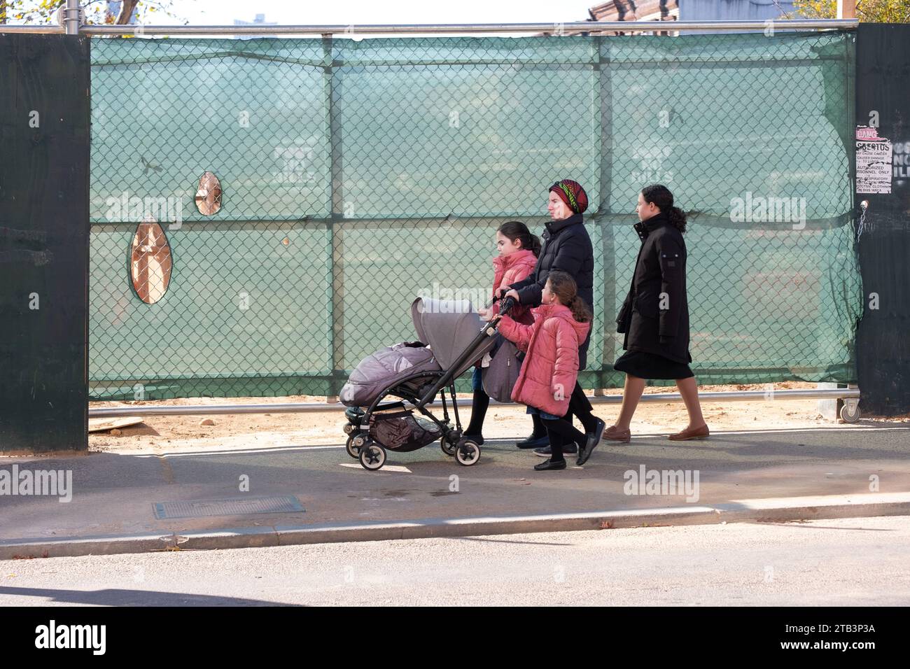 Une femme orthodoxe et ses 4 enfants passent devant un chantier de construction sur Lee Avenue à Williamsburg, Brooklyn, New York. Banque D'Images