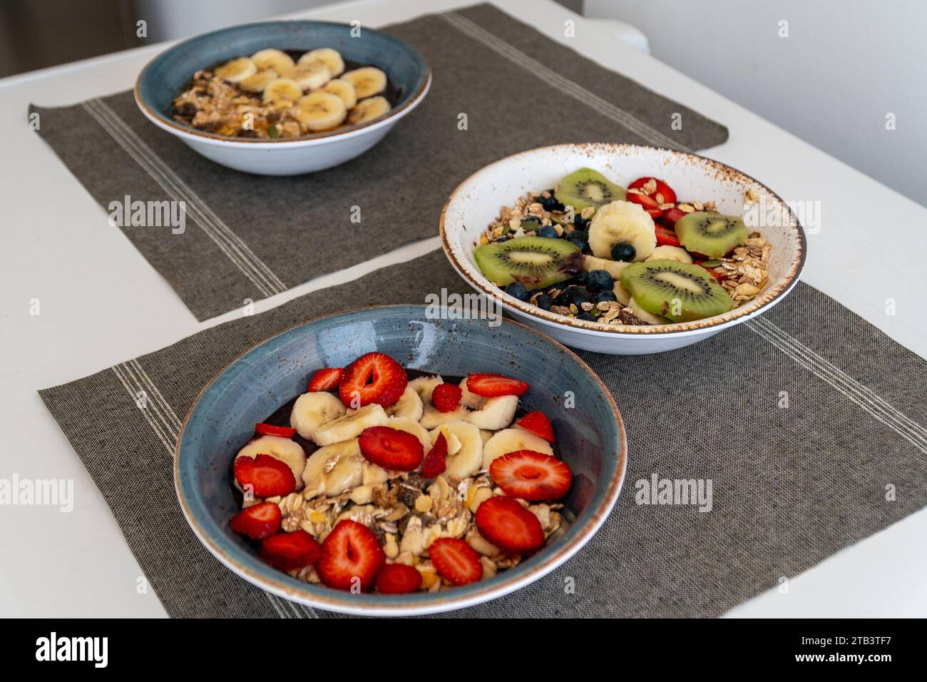 une image de divers bols de crème glacée d'açai surmonté d'une sélection de fruits frais sains et de flocons d'avoine. Banque D'Images