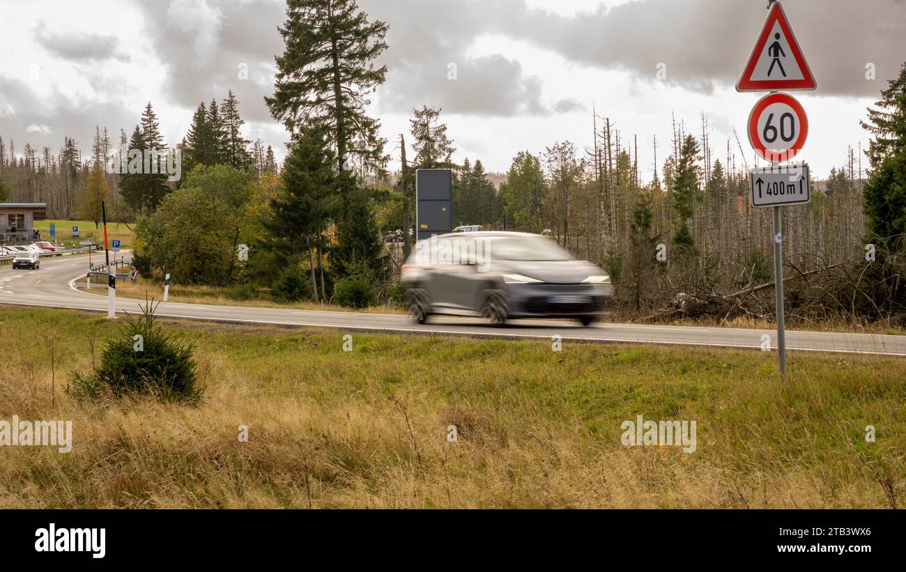 Voiture grise conduisant rapidement sur les rues terrestres au milieu de la forêt nationale dans le Harz basse-saxe dans une zone de limite de vitesse de 60 km/h le jour Banque D'Images