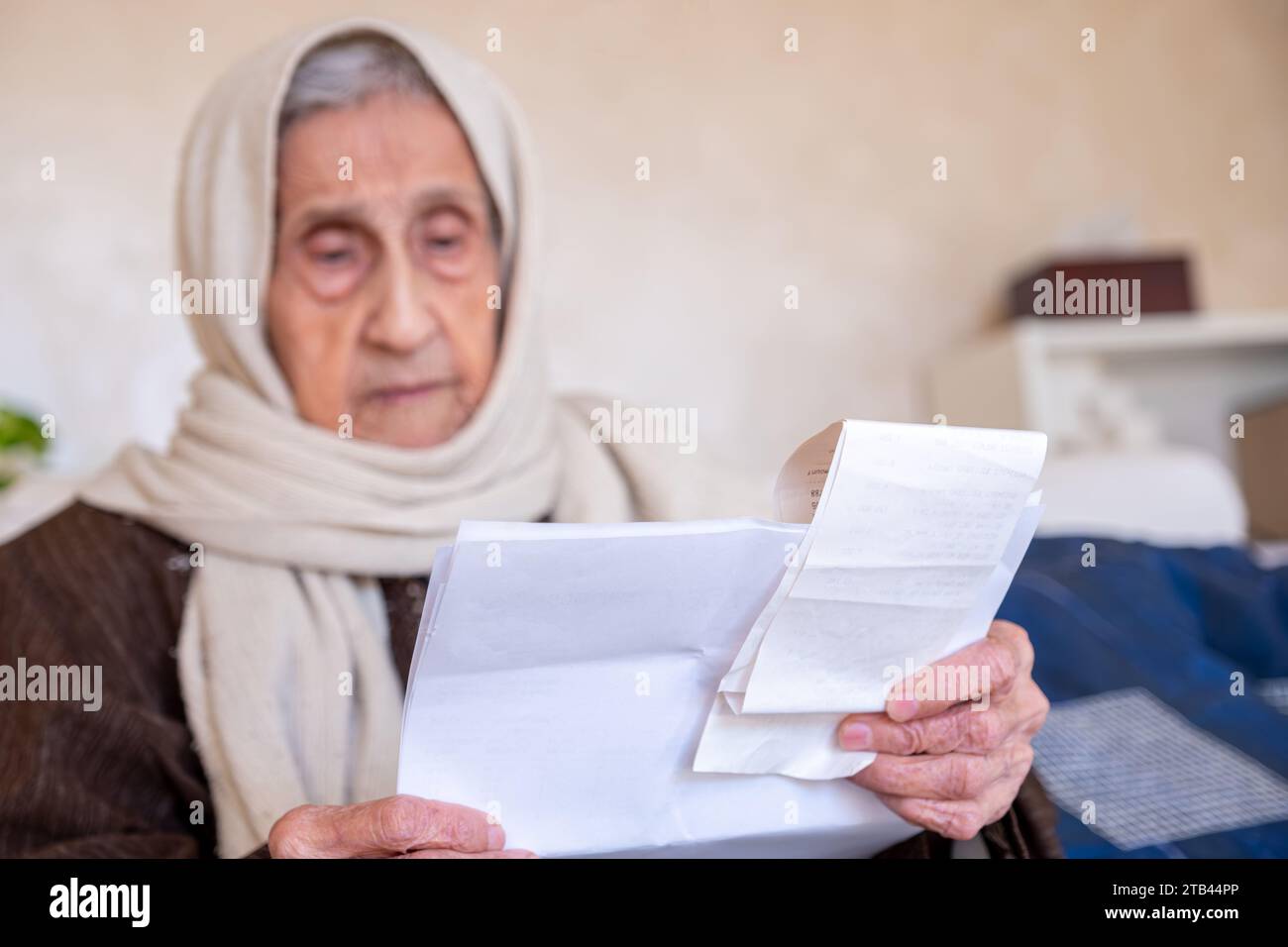 vieille dame tenant le reçu vérifiant le coût de la vie et le loyer de la maison et ses dettes Banque D'Images