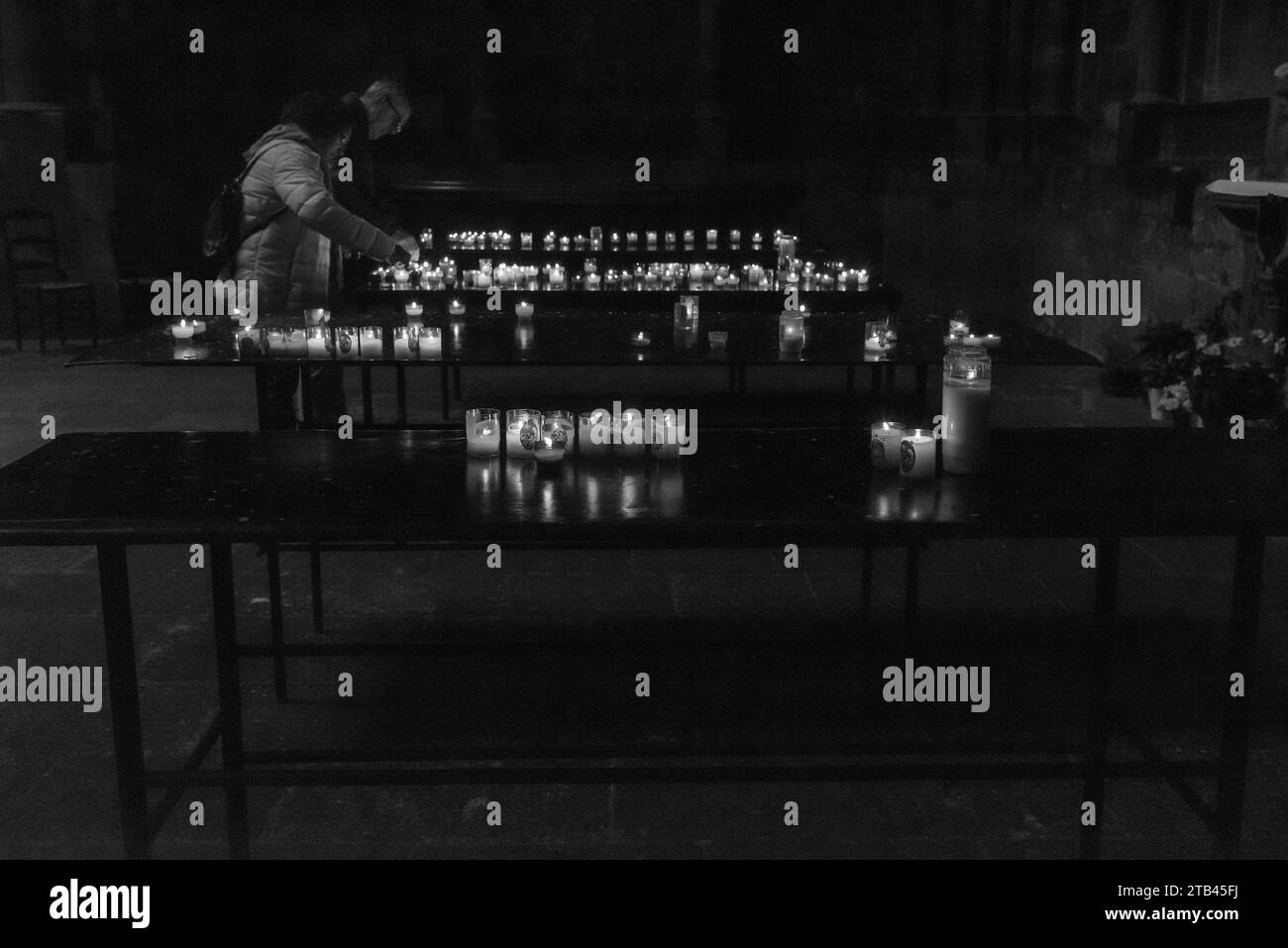 Metz, France - 26 décembre 2022 : couple d'âge moyen allumant des bougies dans la cathédrale Saint-Étienne le lendemain des vacances de Noël. Photo historique noir et blanc. Banque D'Images