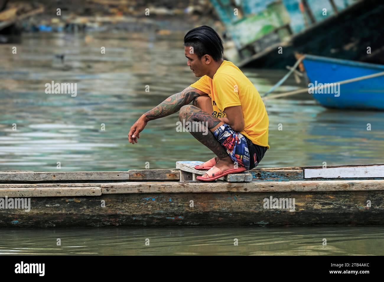 Homme lourdement tatoué sur un canot en bois dans le port de cette capitale provinciale dans l'extrême nord de Sulawesi. Manado, Sulawesi du Nord, Indonésie Banque D'Images