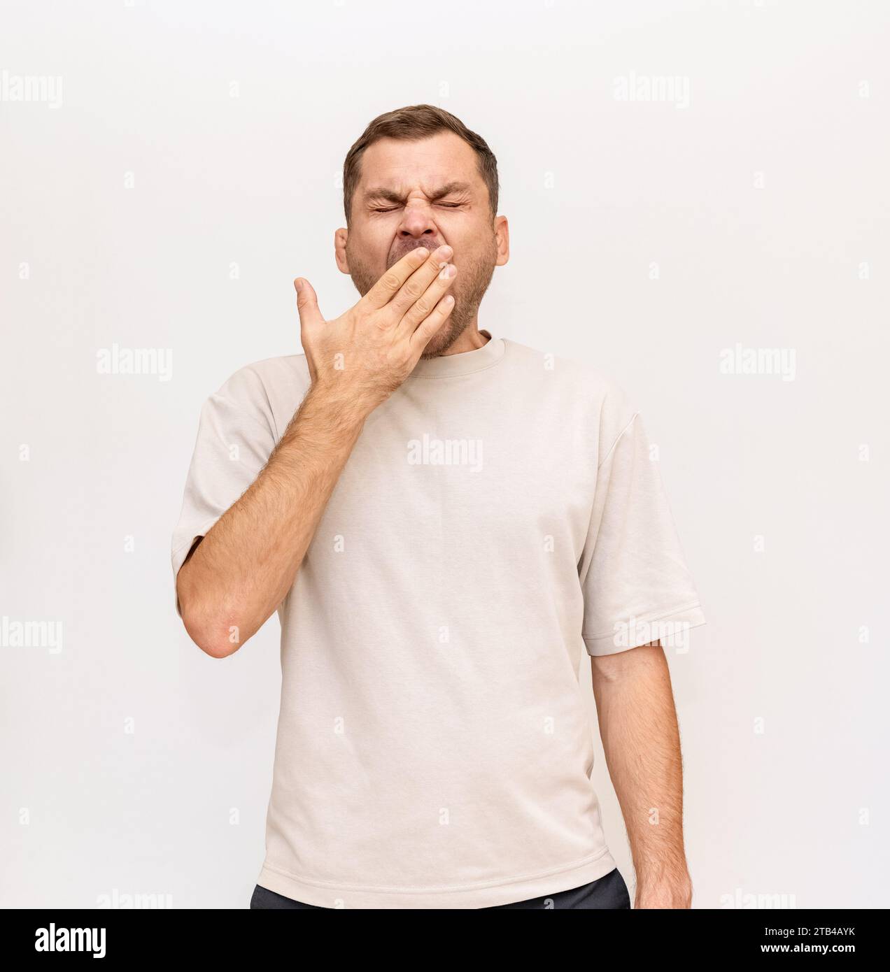 L'homme bâille en couvrant la bouche ouverte avec sa main. Somnolence et ennui. Banque D'Images