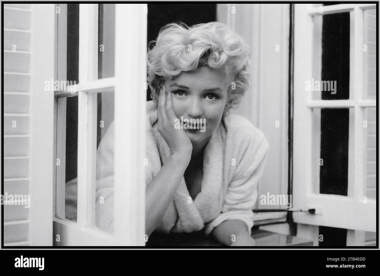 Marilyn Monroe, portrait publicitaire de film ouvert vulnérable pensif, debout à des fenêtres ouvertes dans une pose informelle, noir et blanc 1960s Hollywood USA Banque D'Images