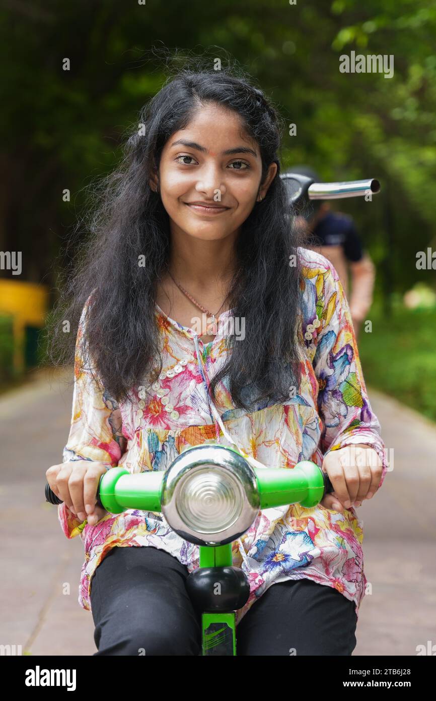 Belle fille indienne chevauchant tricycle de couleur verte. Profiter des vacances d'été dans le parc ou le jardin Banque D'Images