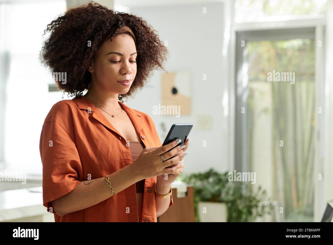 Portrait de femme souriante lisant des messages texte de partenaire sur smartphone Banque D'Images