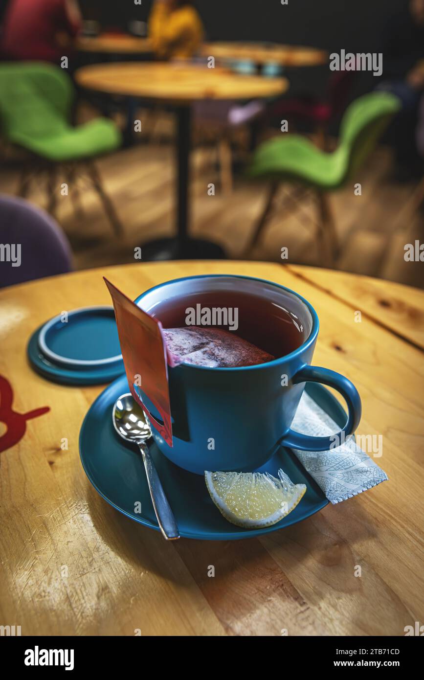 Tasse de thé en céramique bleue servie avec sachet de thé tremper dans de l'eau chaude Banque D'Images