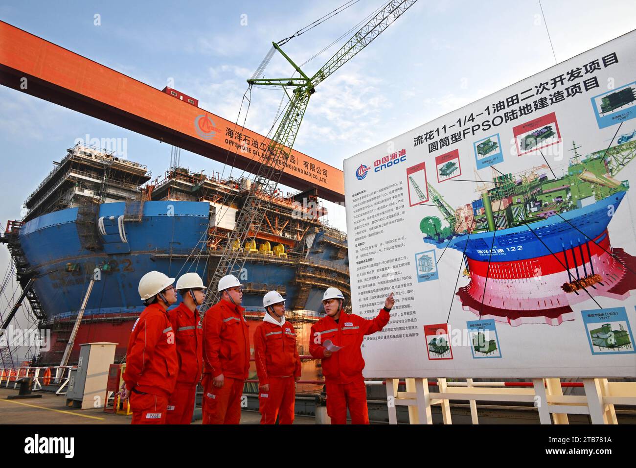 Qingdao, province chinoise du Shandong. 4 décembre 2023. Les ingénieurs communiquent par Haiyang Shiyou 122, la première installation cylindrique flottante, de production, de stockage et de déchargement (FPSO) d'Asie, à Qingdao, dans la province du Shandong de l'est de la Chine, le 4 décembre 2023. Conçu et fabriqué en Chine, Haiyang Shiyou 122 est récemment entré dans sa phase d’assemblage final à Qingdao. Avec un diamètre d'environ 90 mètres et un déplacement prévu de 100 000 tonnes, l'installation est capable de fonctionner pendant 15 ans en mer sans retourner en cale sèche. Crédit : Li Ziheng/Xinhua/Alamy Live News Banque D'Images