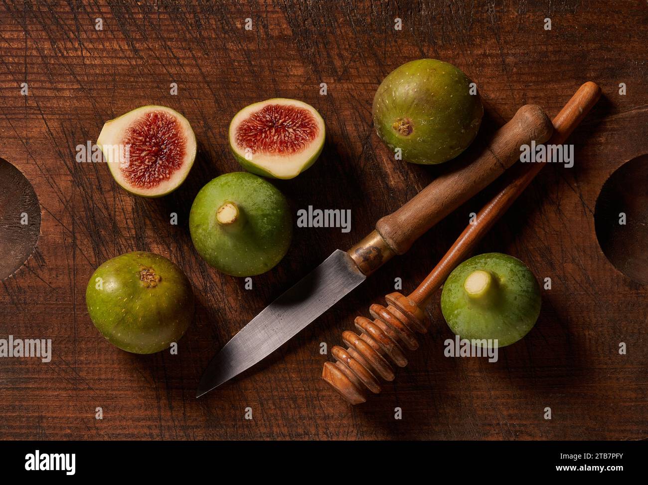 Figues fraîches avec un couteau et une pelle à miel sur une table en bois rustique. Banque D'Images