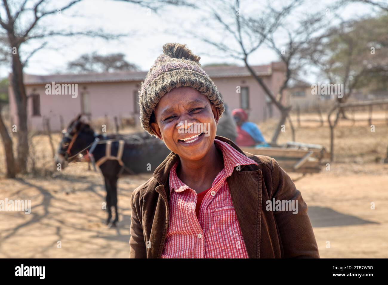 heureuse femme de village africain, riant dans la rue, chemin de terre avec un chariot d'âne en arrière-plan Banque D'Images