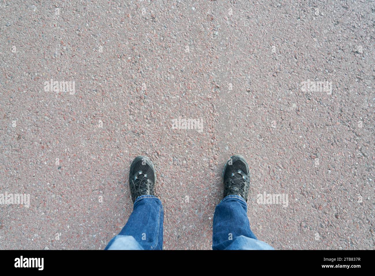 Point de vue avec des chaussures de baskets debout sur une route asphaltée grise Banque D'Images