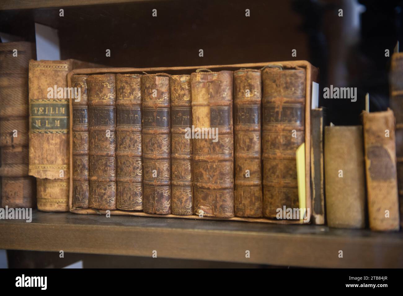 Des livres sacrés juifs poussiéreux, usés et délavés, reliés en cuir, empilés verticalement sur une étagère de bibliothèque. Banque D'Images