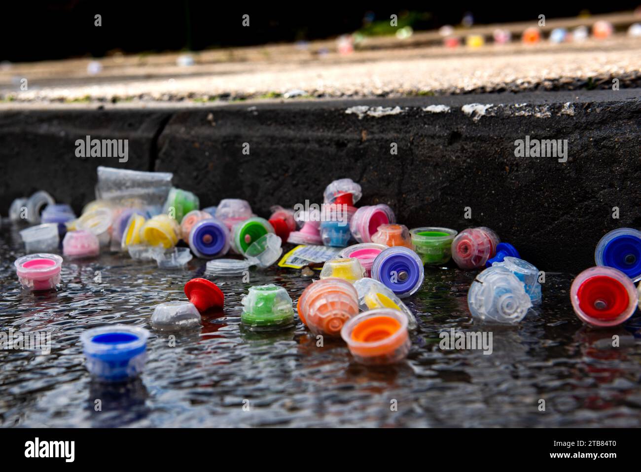 Les bouchons de bouteilles d'eau en plastique multicolores reposent sur une rue mouillée et pavée pendant la course du marathon de Jérusalem. Banque D'Images