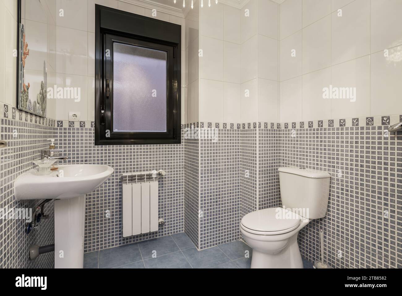 Une salle de bain avec grès et carrelage blanc, une bordure de séparation, lavabo en porcelaine, toilettes assorties Banque D'Images