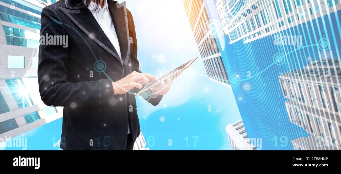 Femme d'affaires tenant la tablette et touchant le réseau économique numérique et la technologie d'analyse de données sur gratte-ciel financier moderne Banque D'Images