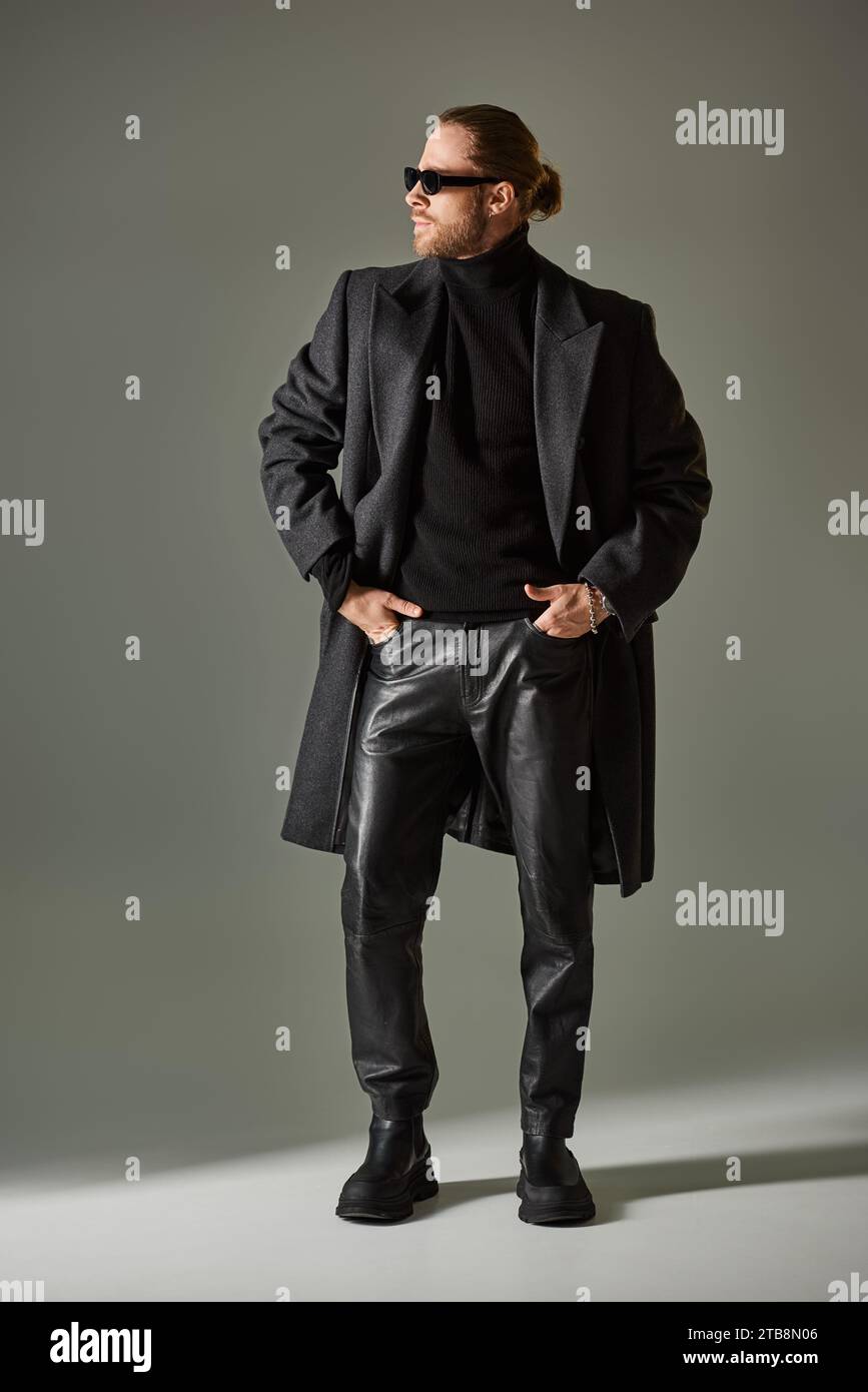 pleine longueur de beau modèle masculin dans les lunettes de soleil et tenue noire debout avec les mains dans les poches Banque D'Images