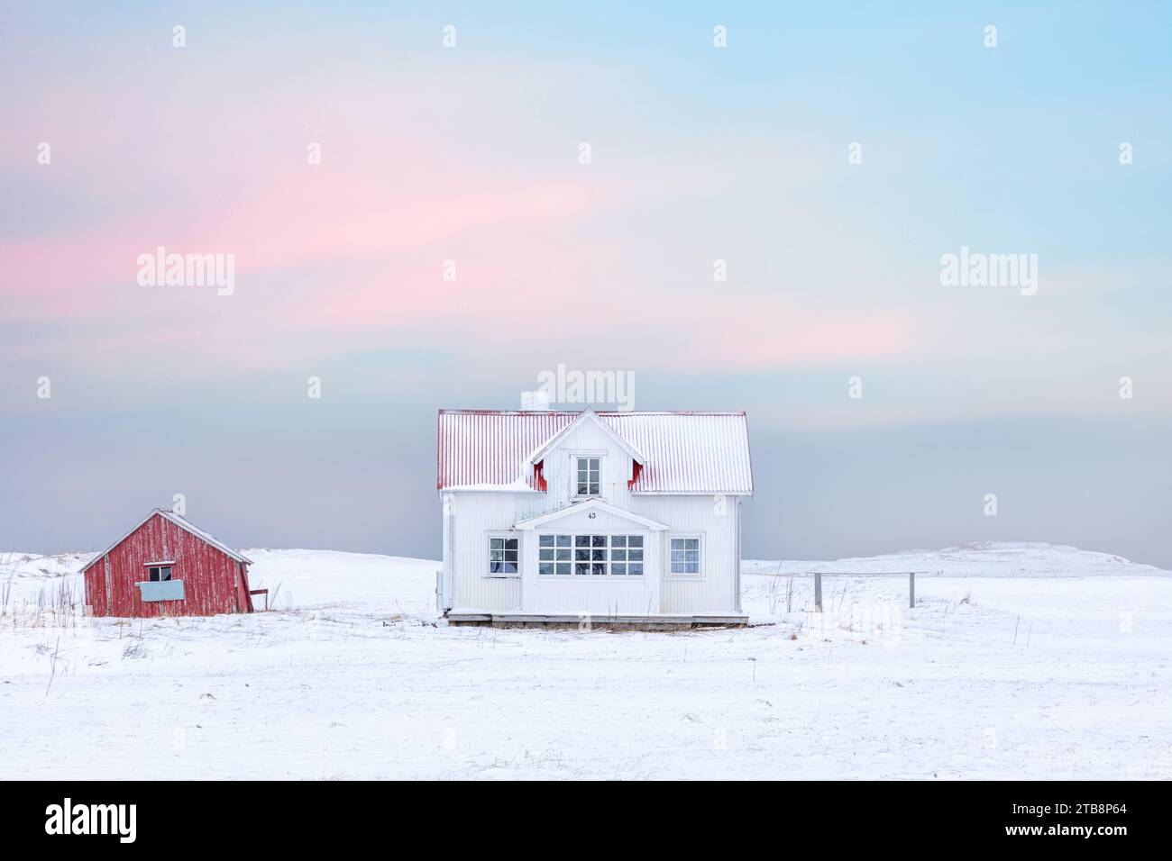 Une maison solitaire en bois blanc avec un toit rouge dans la neige sur les îles Lofoten en Norvège. Banque D'Images