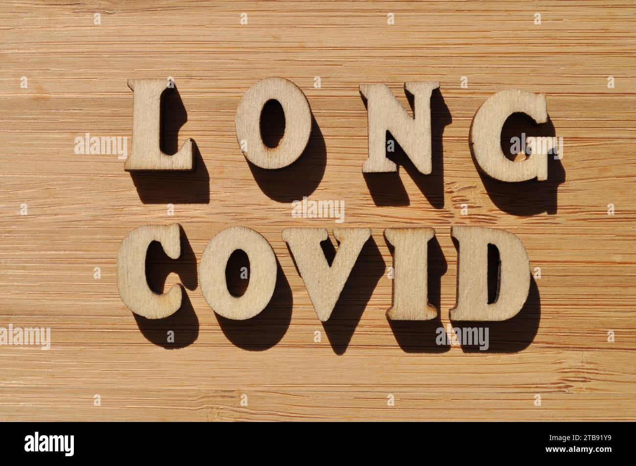 Long Covid, mots en lettres de l'alphabet en bois isolés sur fond de bois Banque D'Images