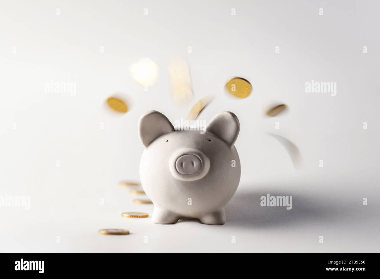 Les pièces d'or se déversent dans une tirelire par le haut. Boîte d'argent de porc avec des pièces d'or tombant Banque D'Images