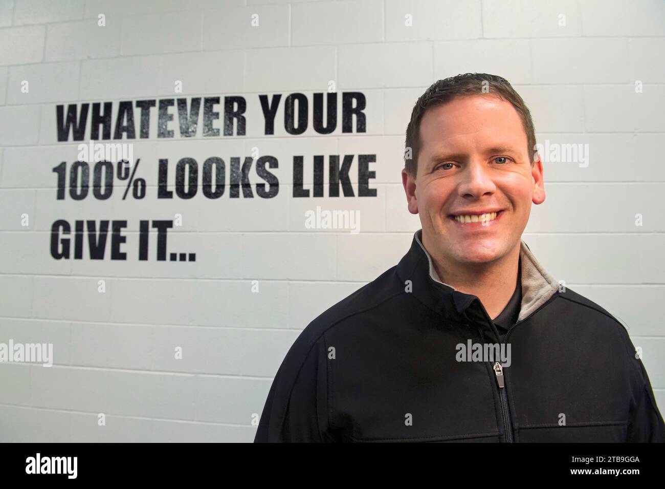Homme mûr se tient devant un signe de motivation sur un mur ; Lincoln, Nebraska, États-Unis d'Amérique Banque D'Images