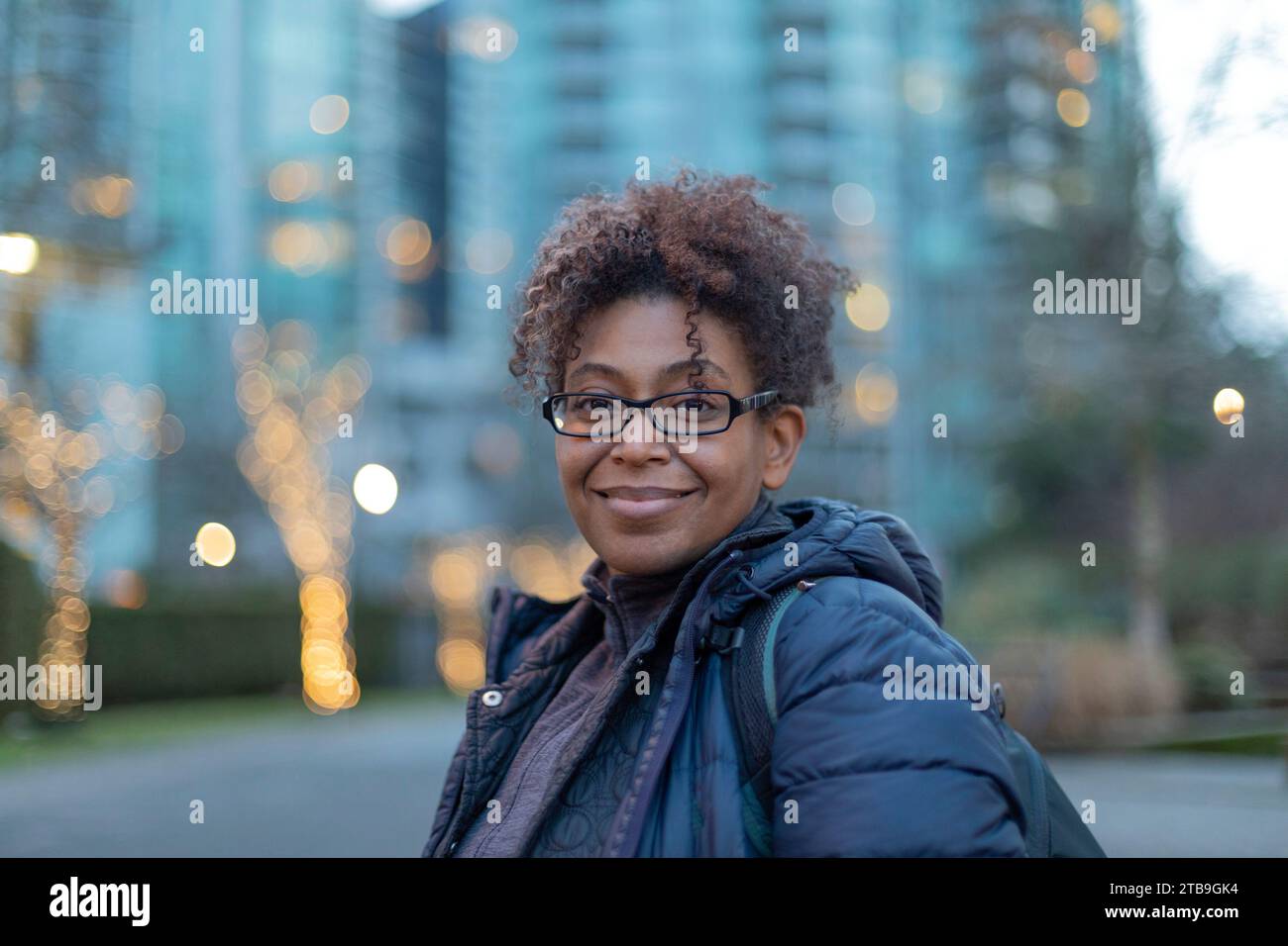 Portrait rapproché d'une femme debout dehors à Vancouver au crépuscule, souriant à la caméra ; Vancouver, Colombie-Britannique, Canada Banque D'Images