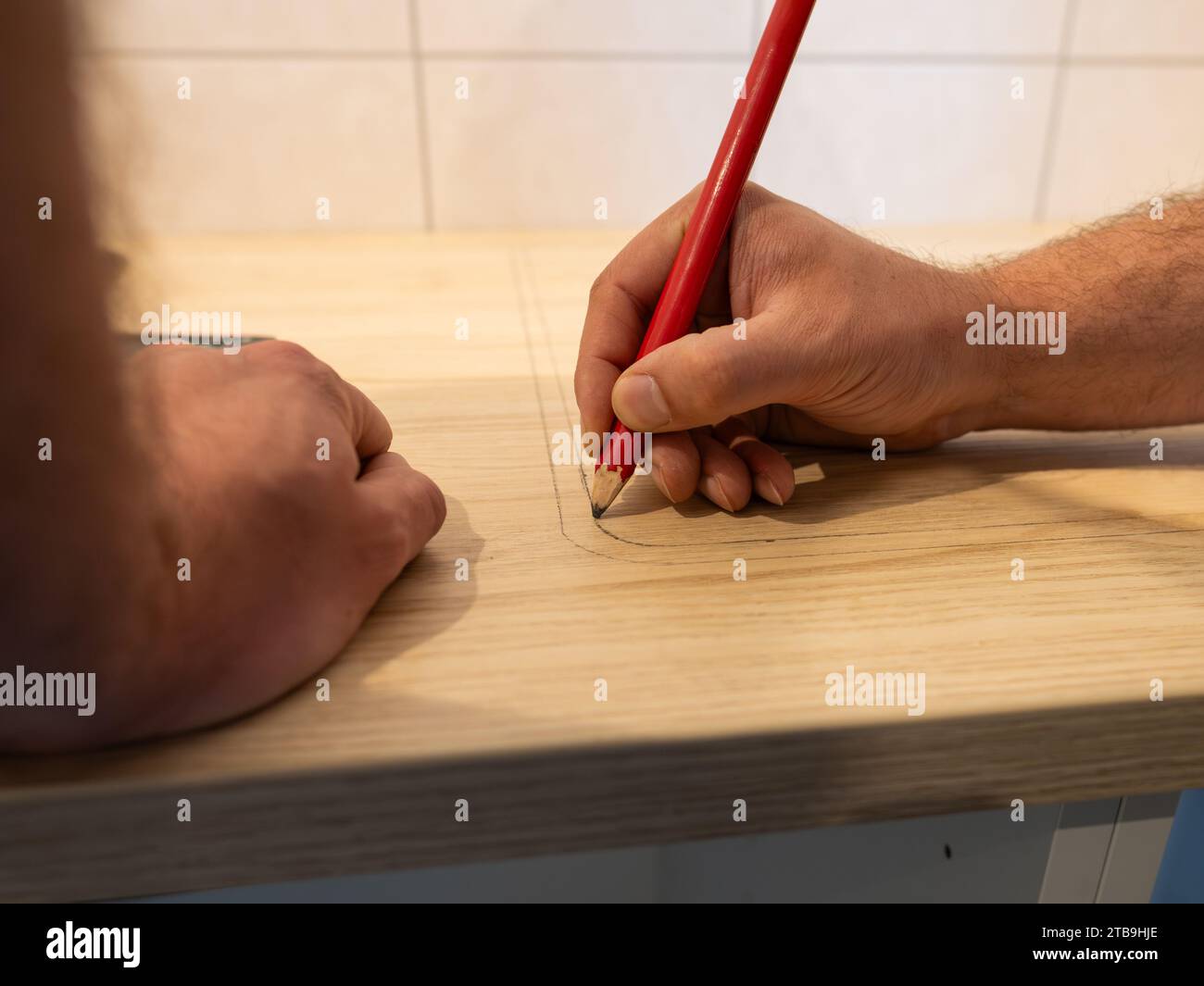 Dessiner une ligne avec un crayon sur un plan de travail. Le charpentier prépare la pièce en bois pour la scier. Construire une nouvelle cuisine dans un appartement. Travailler à domicile. Banque D'Images