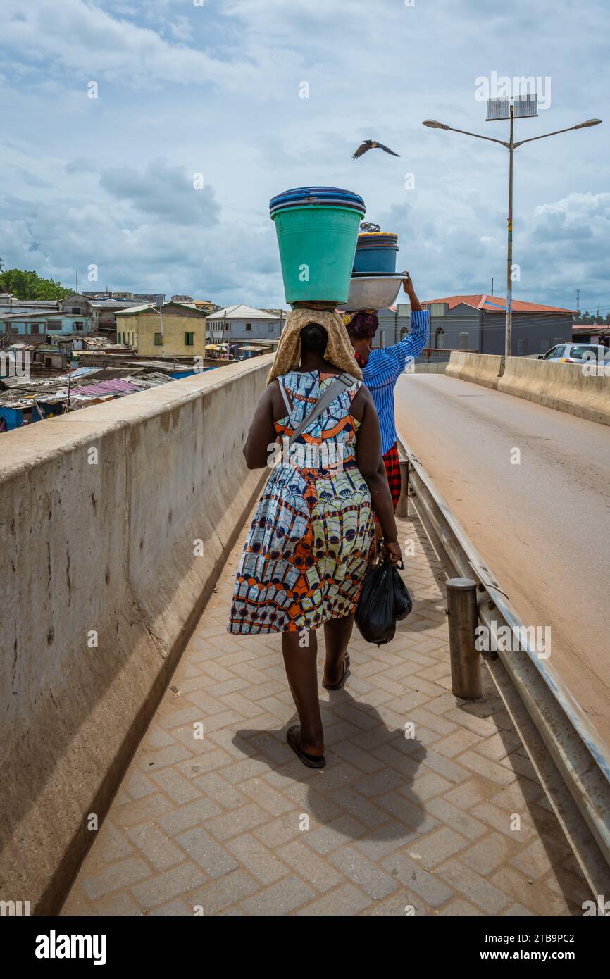 Deux femmes ghanéennes vues de derrière portant des seaux sur la tête à Elmina, Ghana, Afrique. Banque D'Images