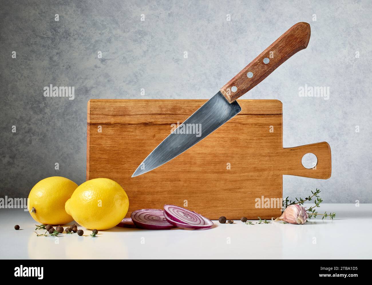 planche à découper en bois et couteau lévitant sur fond gris Banque D'Images