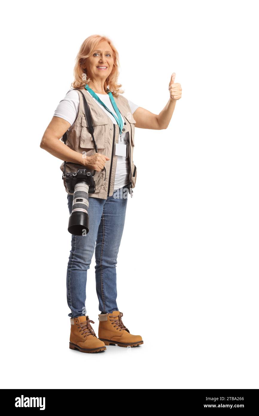 Photo en pied d'une photographe féminine avec un appareil photo sur bandoulière faisant gester les pouces vers le haut isolé sur fond blanc Banque D'Images