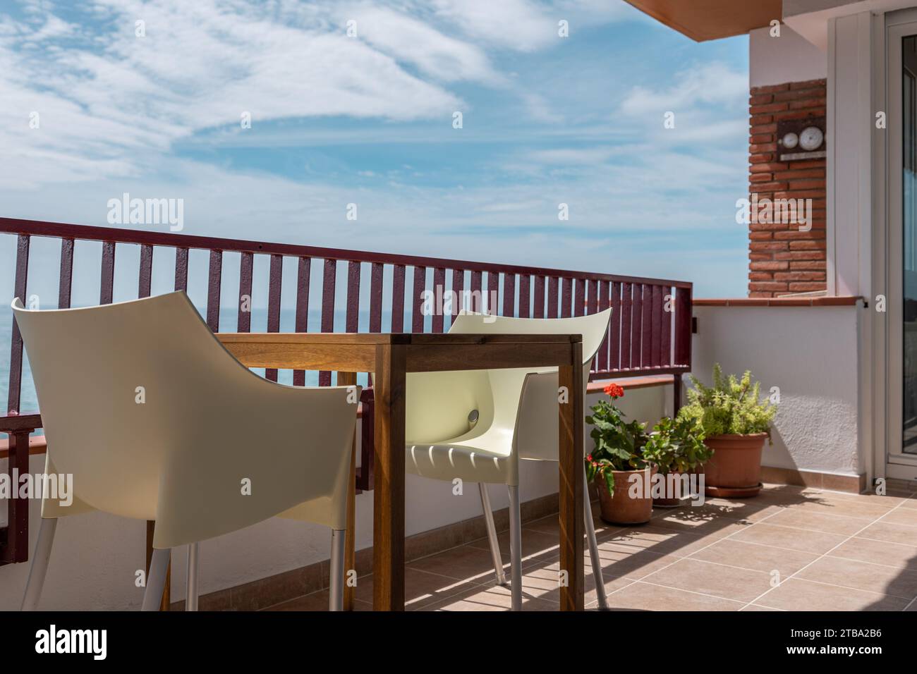 Table en bois avec fauteuils confortables sur le balcon ensoleillé de l'hôtel Banque D'Images