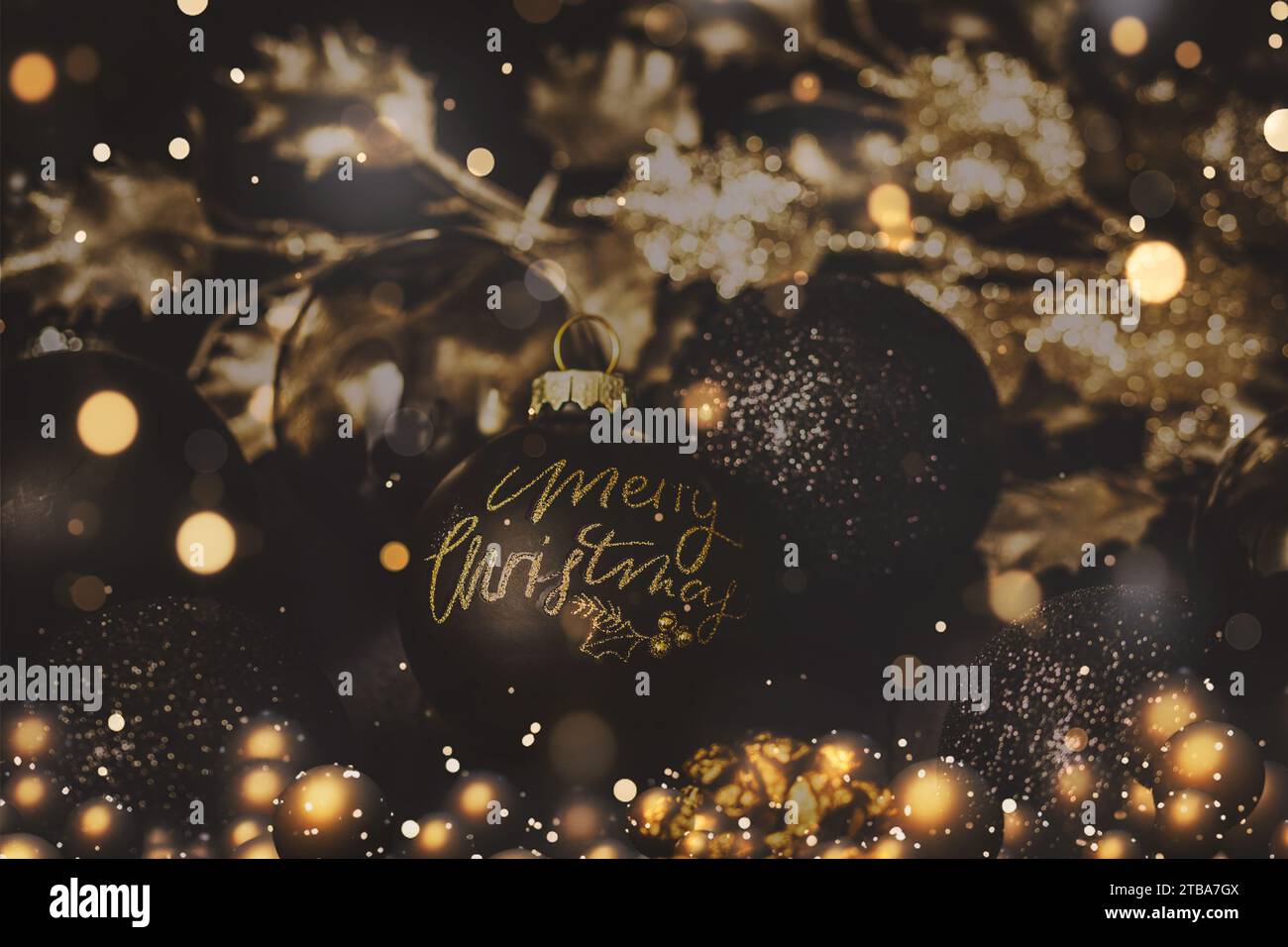 Boule noire avec texte Joyeux Noël, boules noires et dorées et autres décorations de noël. Banque D'Images