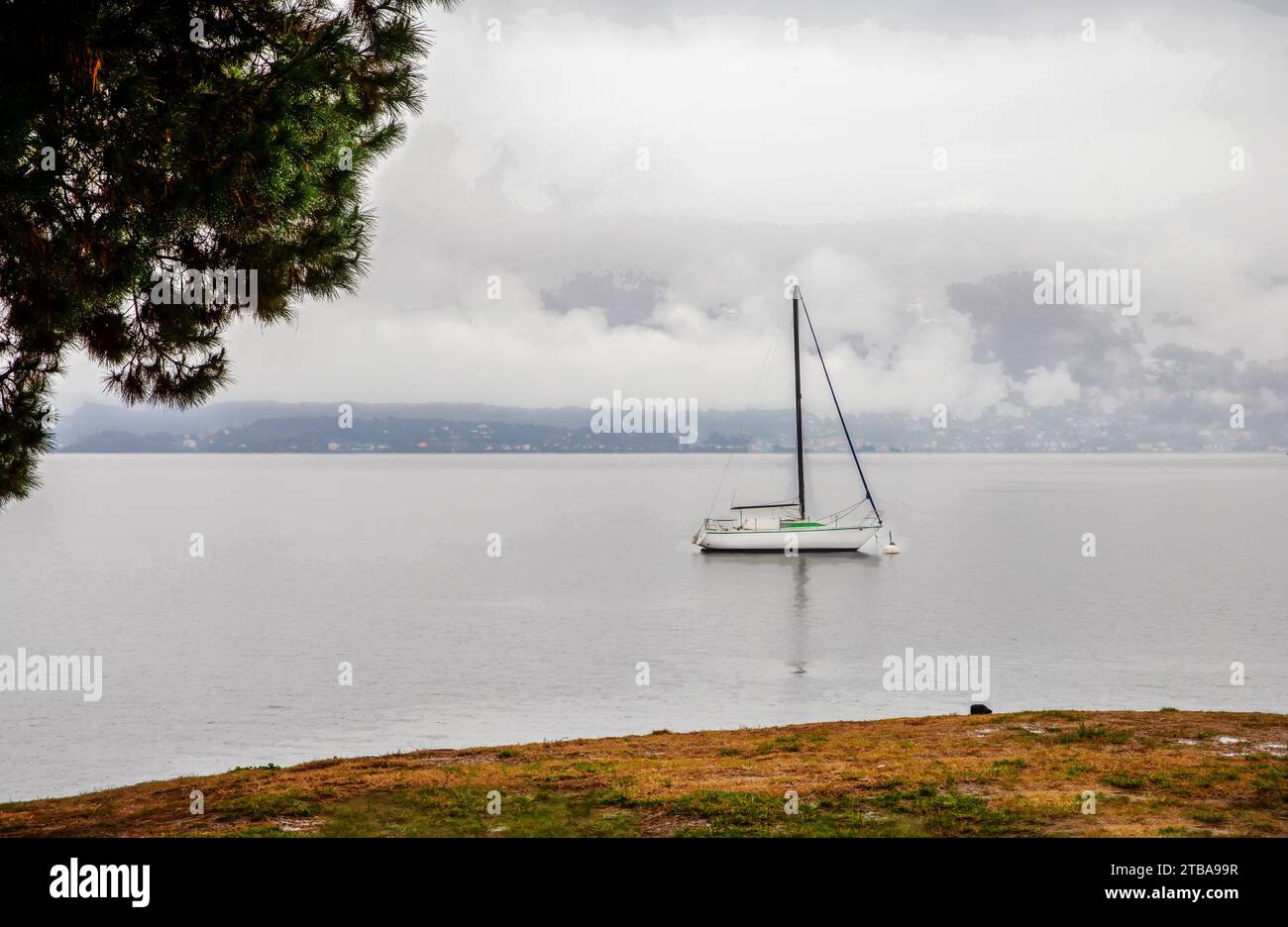 Superbe paysage brumeux sur le lac majeur et voilier ancré à côté de la rive et de l'autre côté du lac : bâtiments - petit sur la distance. Banlieue de Locarno TOW Banque D'Images